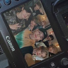 a group of young people are taking a photo on a digital camera with their friends