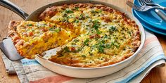 a casserole with cheese and herbs in a dish on a wooden table next to a blue plate