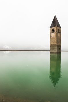 a large tower sitting on top of a green lake next to a shore covered in water