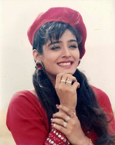 a woman wearing a red hat and holding her hand on her chin, smiling at the camera