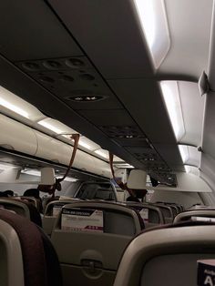 the inside of an airplane with many seats and lights on it's ceiling area