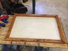 a wooden frame sitting on top of a workbench with tools and supplies around it