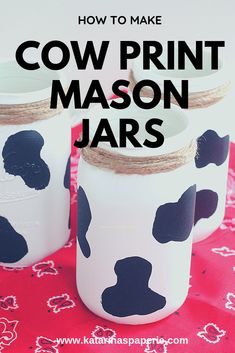 three mason jars with black and white cow print painted on them sitting on a red tablecloth