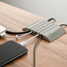 an electronic device connected to a laptop on a wooden table with a charger plugged into it