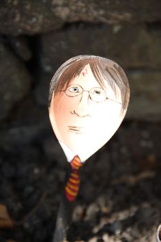 a close up of a wooden spoon with a person's face painted on it