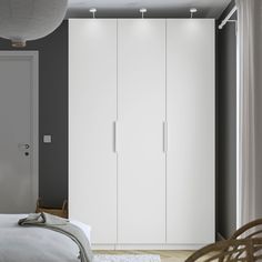 a bedroom with a bed and white cupboards next to a door on the wall