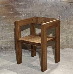 a wooden chair sitting on top of a cement floor next to a brick wall with a hole in it