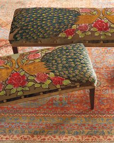 two benches with floral designs on them sitting in front of a colorful carpet and rug