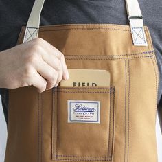 a person wearing an apron holding a business card in their pocket with the name field on it