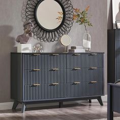 a blue and black dresser with a mirror on the wall next to it, in front of a gray wall