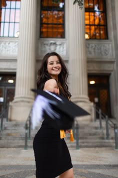 a woman in a black dress is walking down the street with her graduation hat on