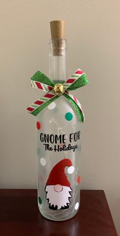 an empty glass bottle with a santa clause on it and a green ribbon tied around the top