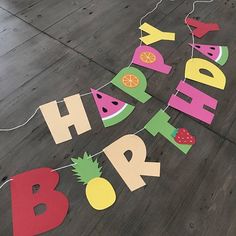 a happy birthday banner made out of cutout paper fruit and letters on a wood floor