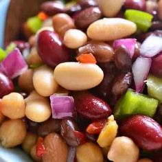 beans and onions are mixed together in a blue bowl with a spoon on the side