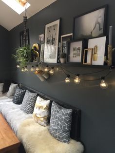 a bed with pillows and lights on the headboard in a room that has dark walls