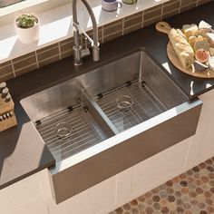 two stainless steel sinks in a kitchen next to a cutting board and utensils