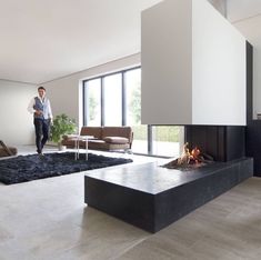 a man is standing in the middle of a living room with fireplace and couches