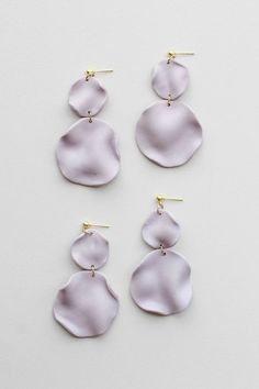 three pairs of white earrings on a white surface