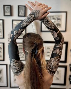 a woman with tattoos on her arm and arms is holding up her hands to the side