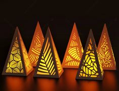 three triangular shaped paper lamps with leaves on them, one is yellow and the other is orange