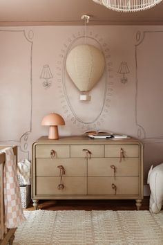 a room with a dresser, lamp and rug on the floor in front of it