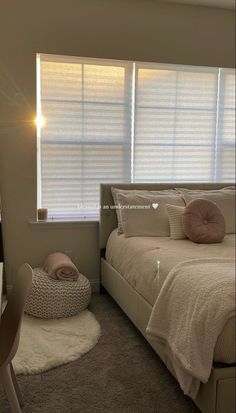 a bedroom with a bed, chair and desk in front of a window that has blinds on the windowsill