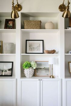 some white shelves with pictures and plants on them