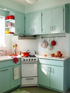 a white stove top oven sitting inside of a kitchen next to a sink and cabinets