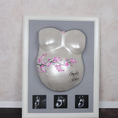 a white framed photo with pink flowers in the shape of a woman's breast