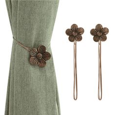 two hair pins with flowers on them next to a green dress and brown tie clip