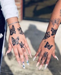 two hands with butterfly tattoos on them and one holding the other's hand out