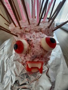 a cake with sticks sticking out of it's face and eyes on tin foil