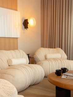 a living room with two couches and a coffee table in front of a curtained window