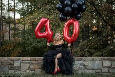 a woman sitting on a wall with balloons in front of her and the number 40