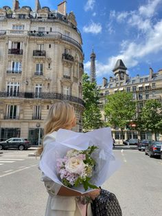 a woman holding a bouquet of flowers in front of a building