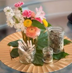 there are many flowers in the vases on this table with pens and pencils