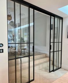 an open glass door leading to a living room and dining area with wood flooring