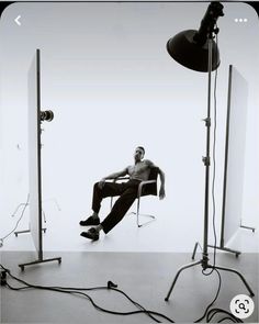 a black and white photo of a shirtless man sitting in a chair between two lights