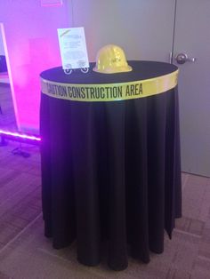 a table with a hard hat on top of it in front of a sign that says caution construction area