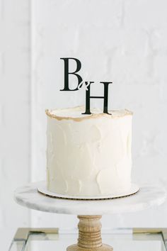 a cake with the letter b and h on top is sitting on a glass stand