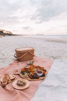 a picnic is set up on the beach with food and drinks in front of it