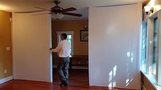 a man is standing in the doorway of his house looking at something on the wall