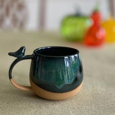 a ceramic coffee cup with a bird handle on the inside sits on a tablecloth