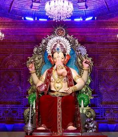 a statue of the god ganesh in front of a chandelier with purple lights