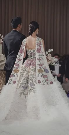 a man and woman standing next to each other in front of a cake on a table