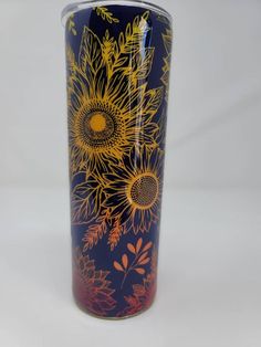 a blue and yellow vase with sunflowers painted on the side, sitting against a white background