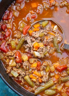 a ladle full of soup with meat and vegetables