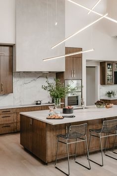 a large kitchen with wooden cabinets and white marble counter tops, along with bar stools