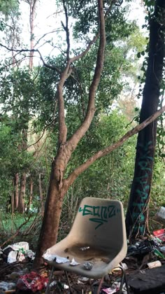 an abandoned chair sitting in the middle of a forest filled with trash and trees,