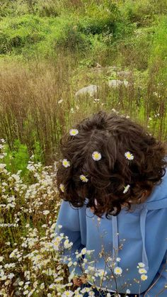 a person standing in a field with wild flowers on their head and looking down at the ground